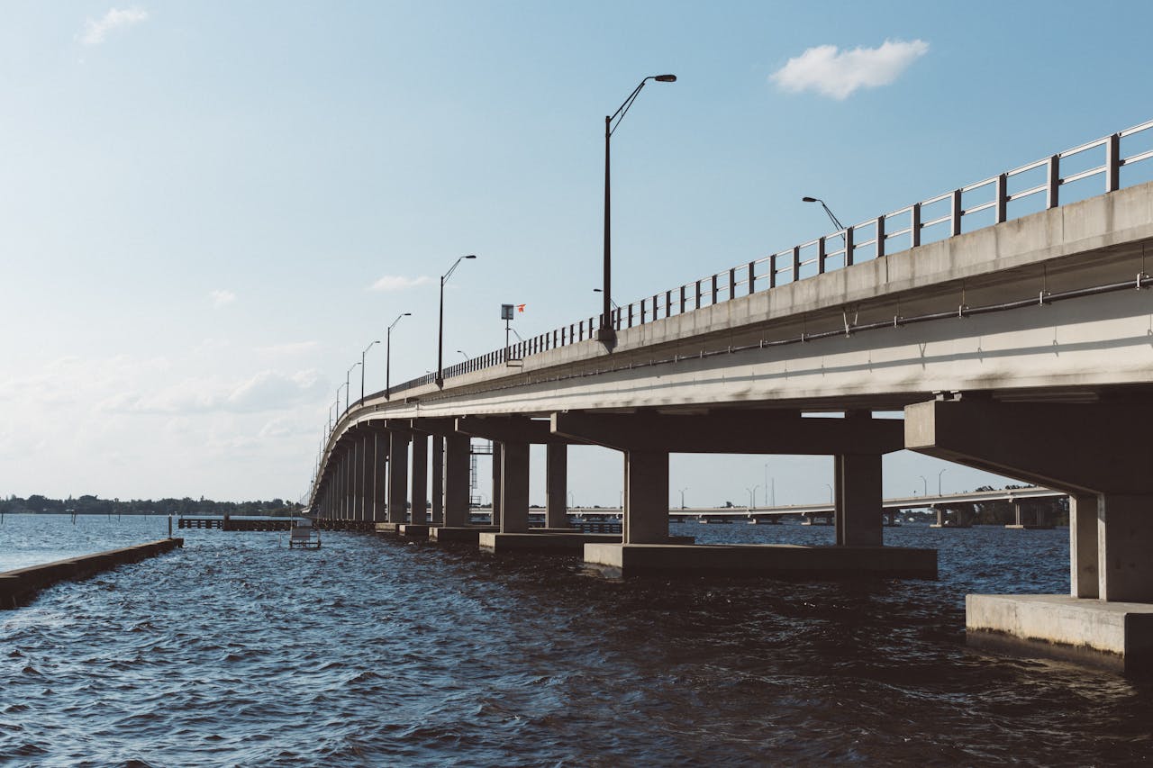 Wide-angle view of a concrete bridge over a river under a clear blue sky, showcasing modern infrastructure.